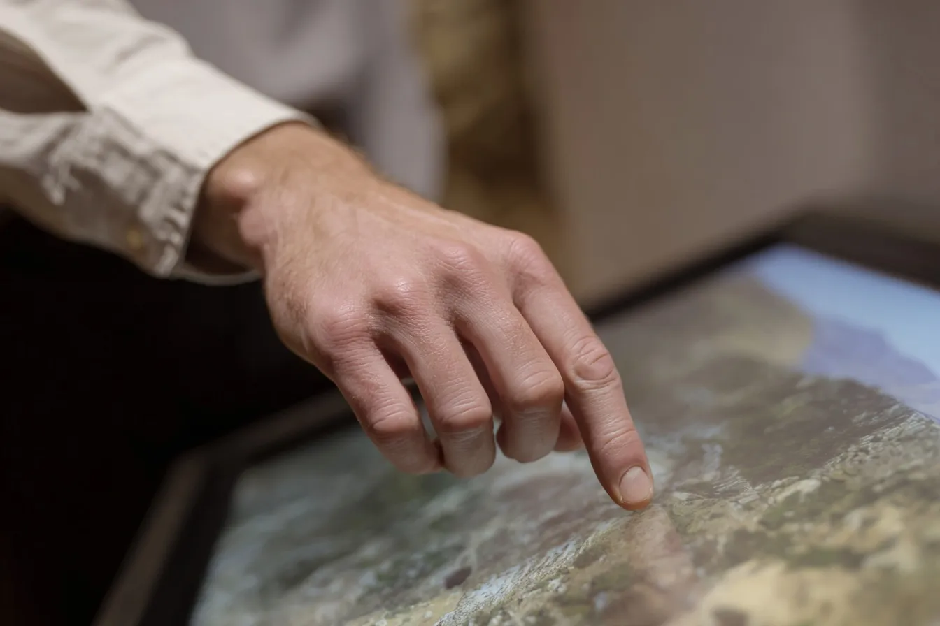 Hand tippt auf interaktiven Touchscreen in der Werkstatt des Ideencampus by LECOS – Prototypenentwicklung und digitale Lösungen für kommunale Verwaltung