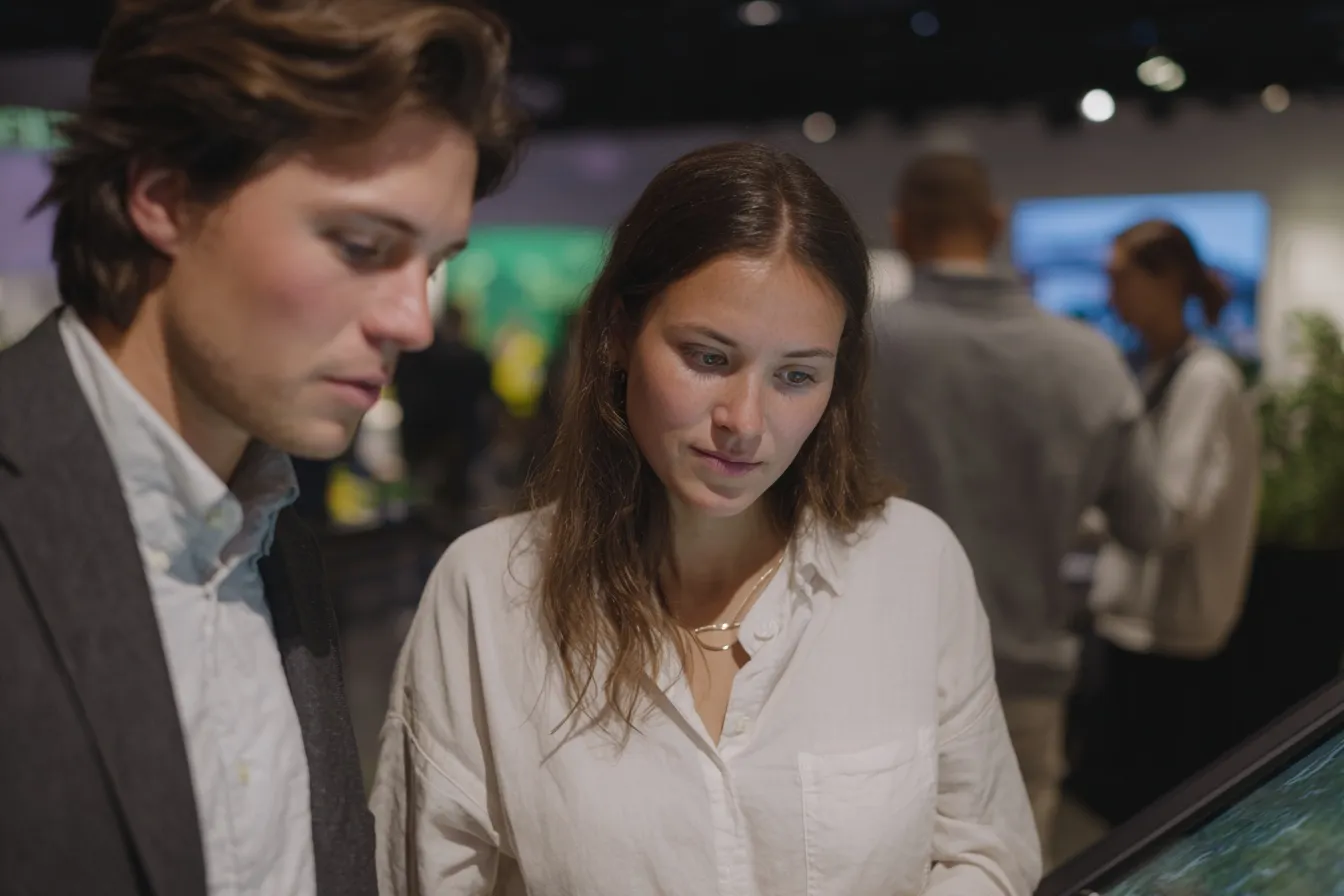 Zwei Personen testen interaktive IT-Lösungen an einem Touchscreen im Atrium des Ideencampus by LECOS – digitale Verwaltung zum Anfassen