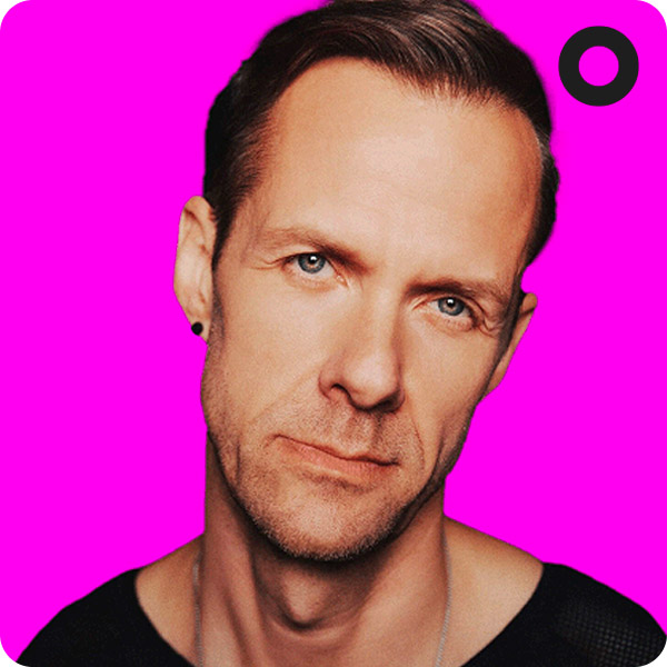 Portrait of DJ Adam Beyer wearing a black top, set against a vibrant pink background