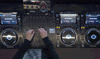 DJ mixing on a professional Pioneer DJ setup with multiple CDJs and a central mixer, adjusting faders and effects in real-time
