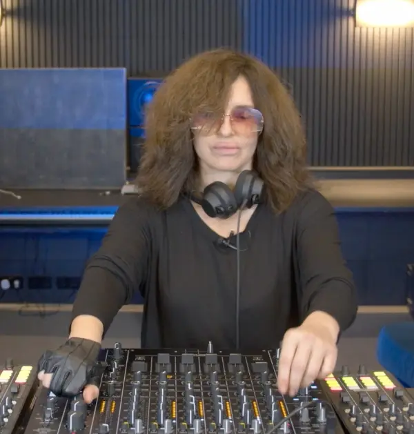 Nicole Moudaber performing on a professional DJ mixer in a studio setting, wearing sunglasses and a performance glove