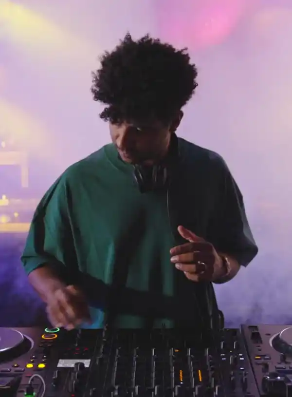 DJ performing on a professional mixer in a club setting with atmospheric lighting and fog effects