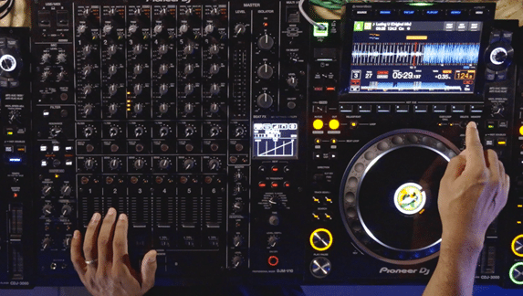 Close-up of a DJ mixing on a Pioneer DJ setup with a professional mixer and CDJ. The screen displays waveforms and track details during live performance