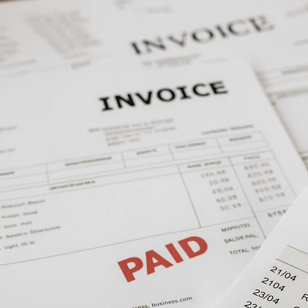 Stack of invoices with financial details, one stamped PAID in red for successful payment processing