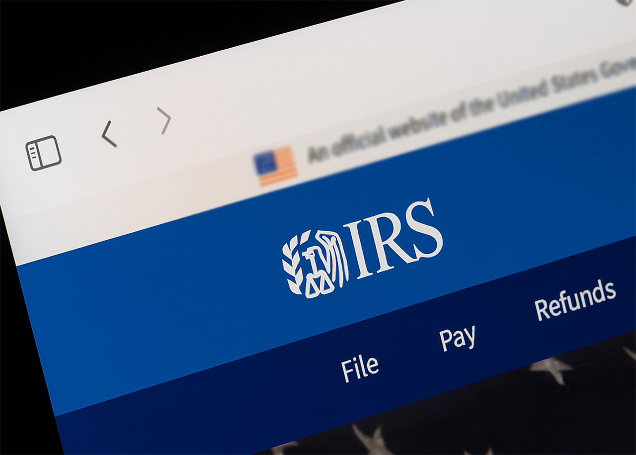 Close-up of the IRS website on a computer screen, showing the IRS logo and navigation menu options: File, Pay, and Refunds.