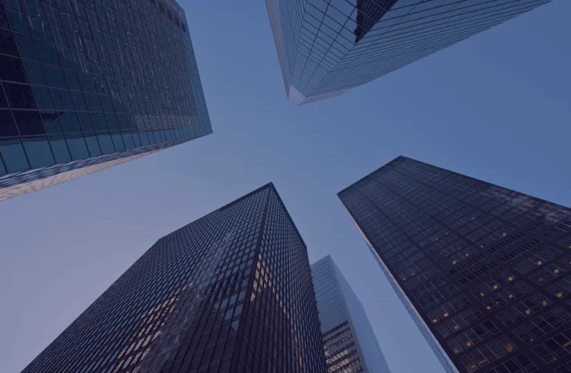 View looking up at tall glass office skyscrapers against a clear blue sky at dusk.