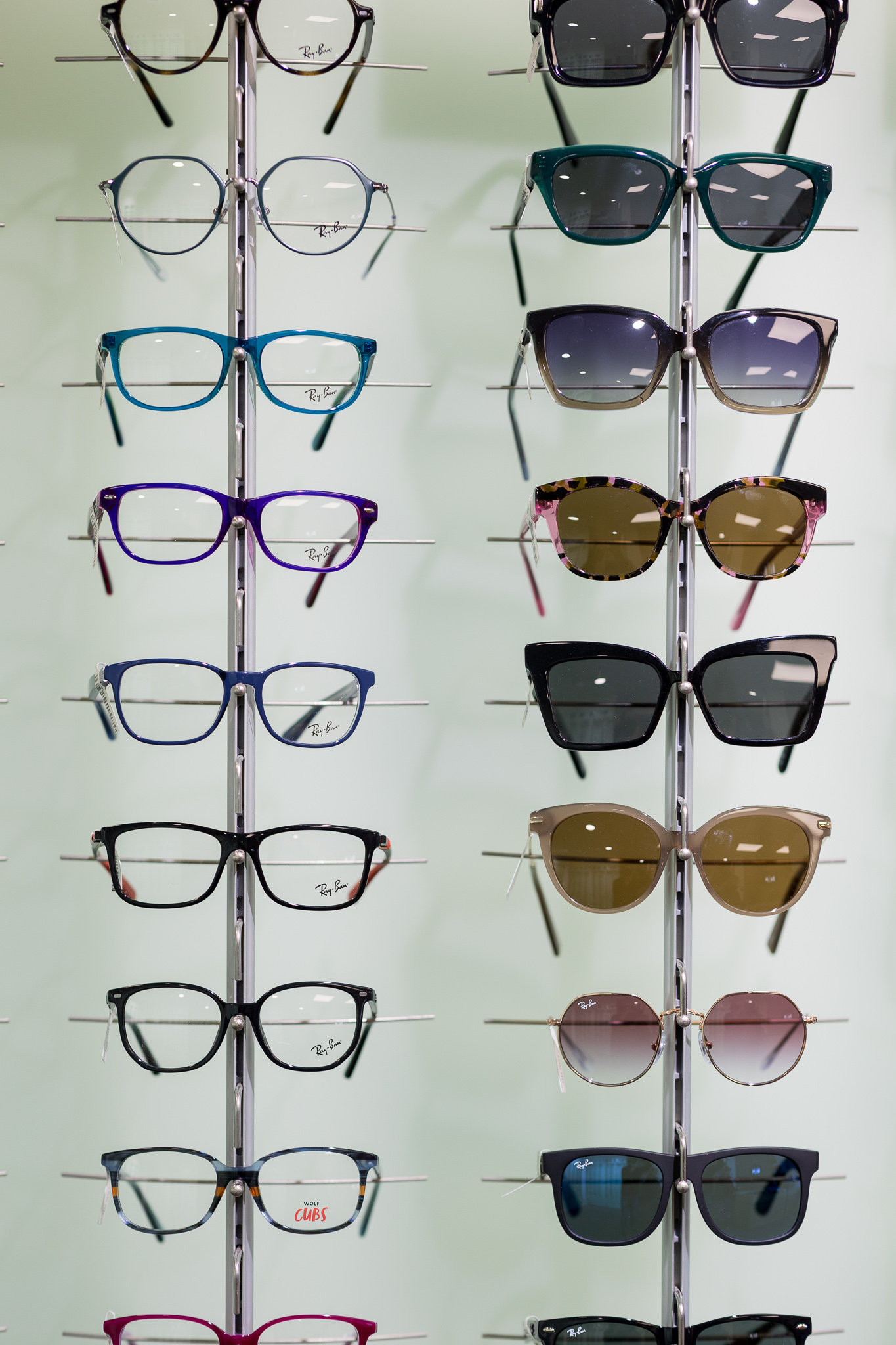 Display stand with rows of Ray-Ban eyeglasses on the left and sunglasses on the right.