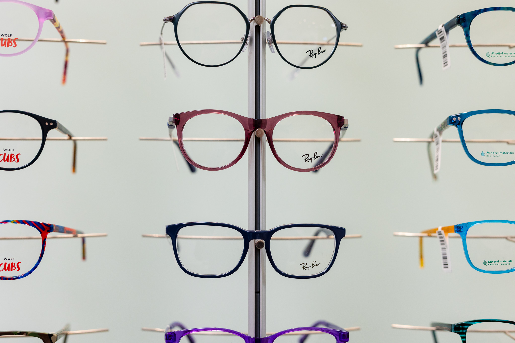 Rows of colorful eyeglass frames displayed on racks in an optical store.