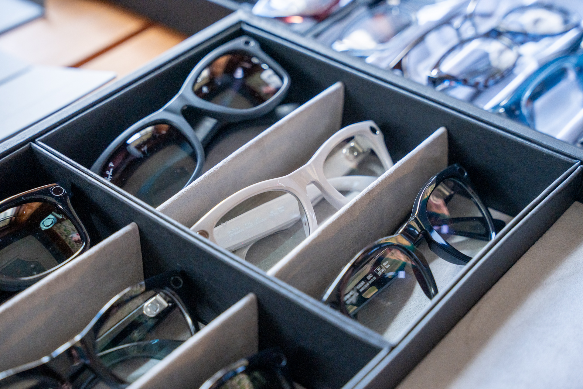 Multiple pairs of eyeglasses with different frame colors in a black divided storage case.