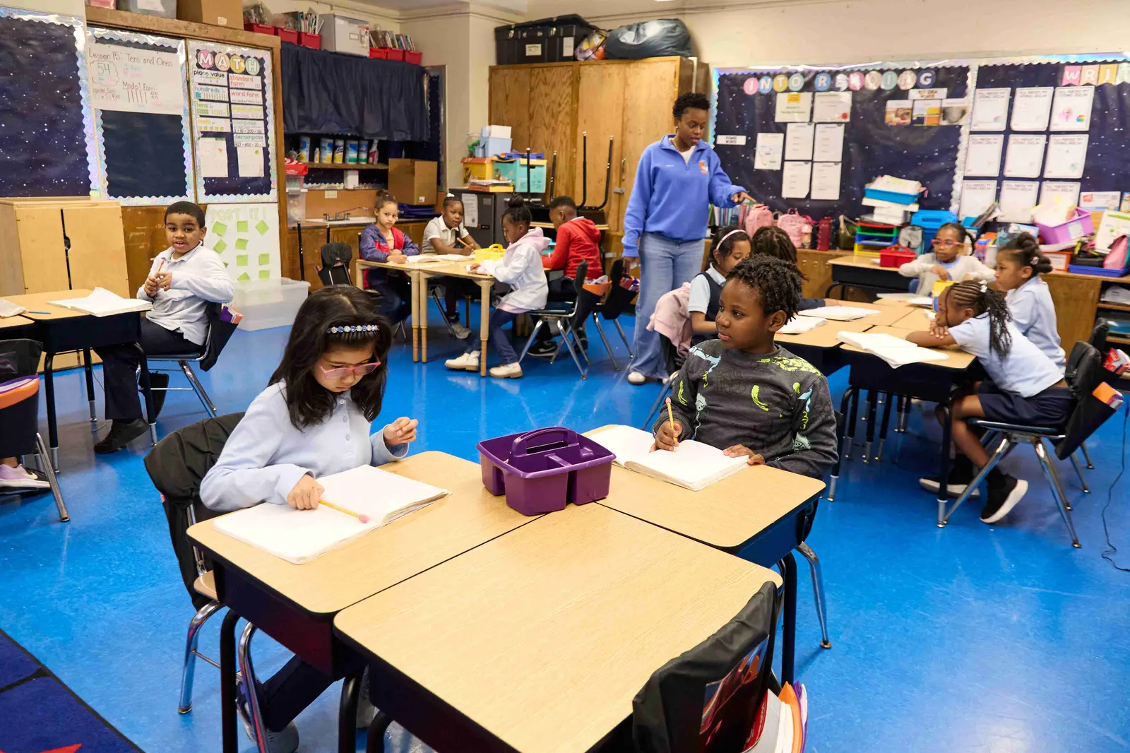 Students working at desks while teacher circulates in elementary classroom