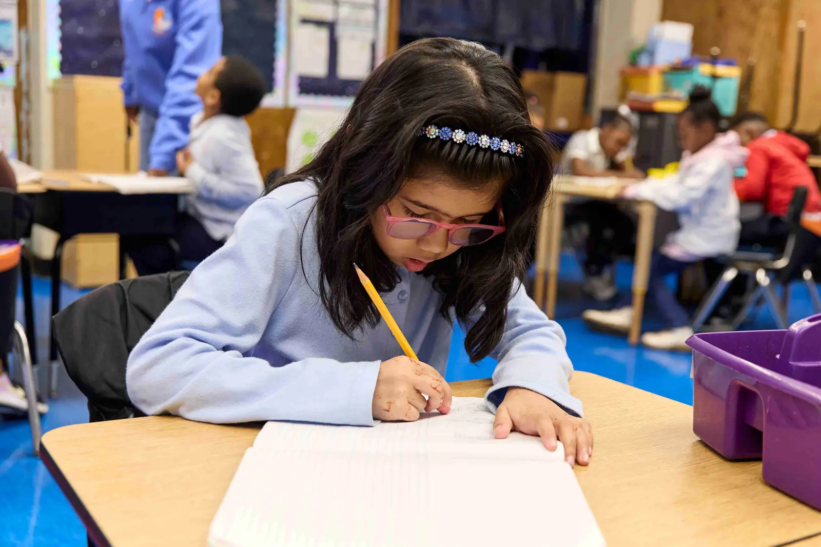 Student writing at desk with pencil during classroom work time