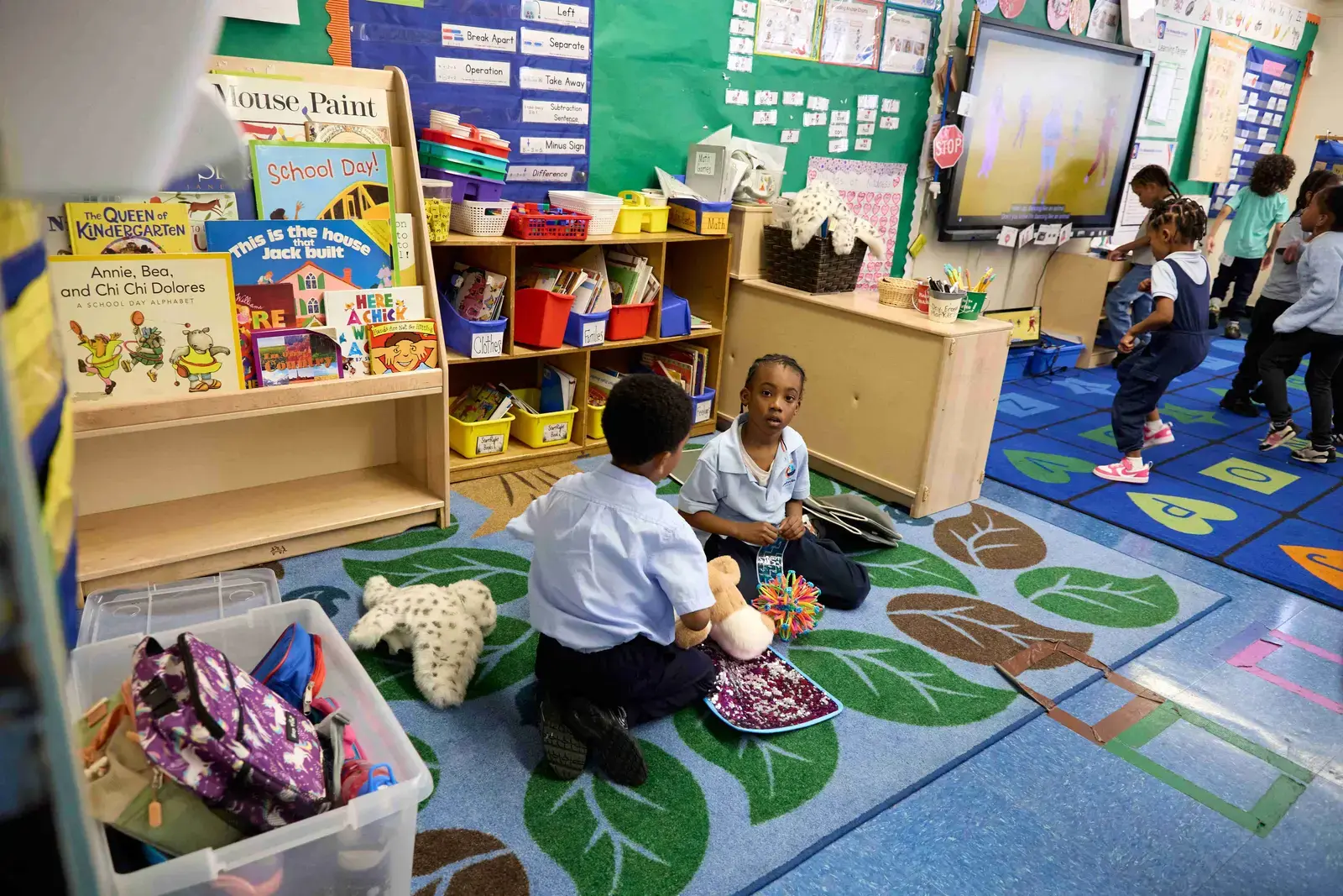 Young students playing and reading together on a colorful classroom rug