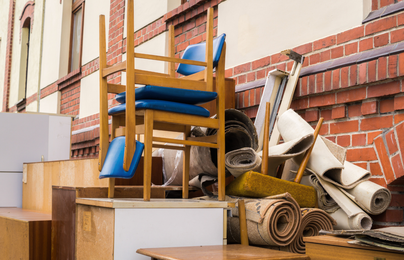 Pile of unwanted furniture, chairs, cabinets, rolled carpet, and renovation debris stacked outside a building, representing professional junk removal and property cleanout services in Medina, Ohio.