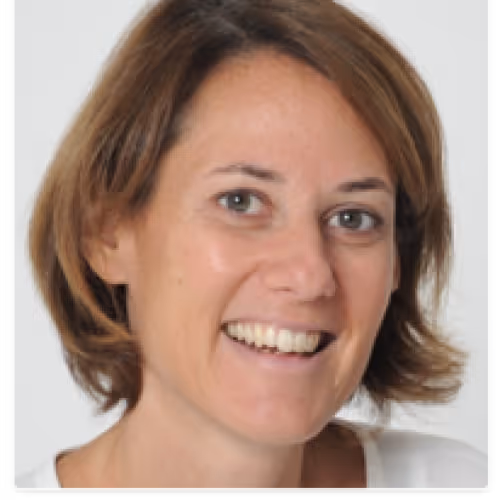 Smiling woman with short brown hair and light-colored eyes wearing a white top.