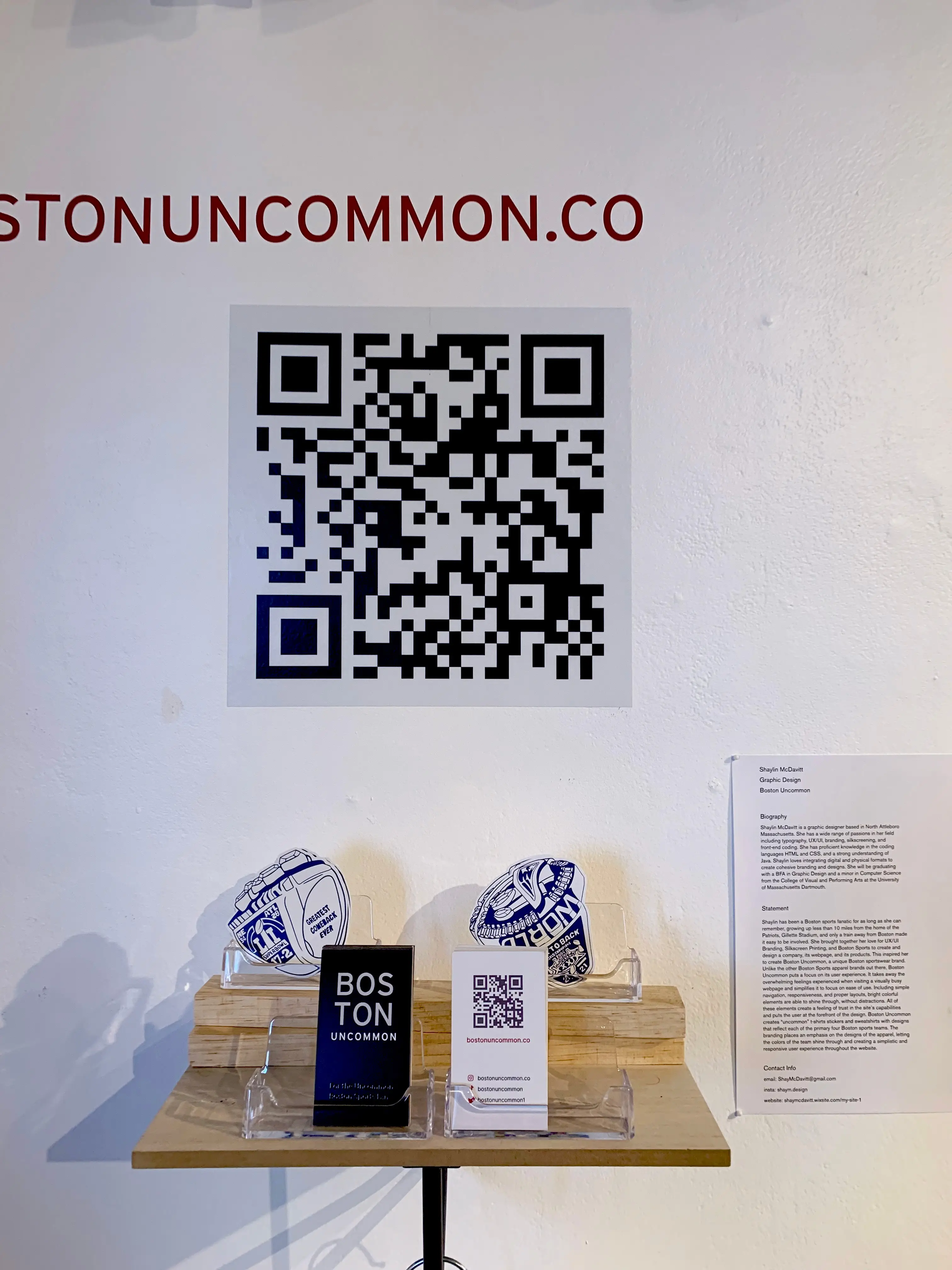 Shelf holding stickers and business cards for Boston Uncommon, as well as a qr code to bostonuncommon.co