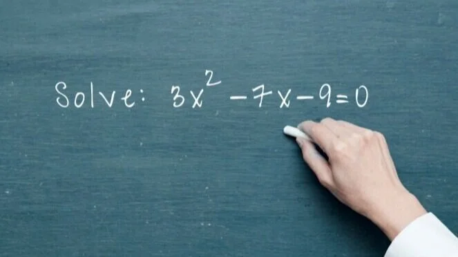 teacher writing math problem on chalk board