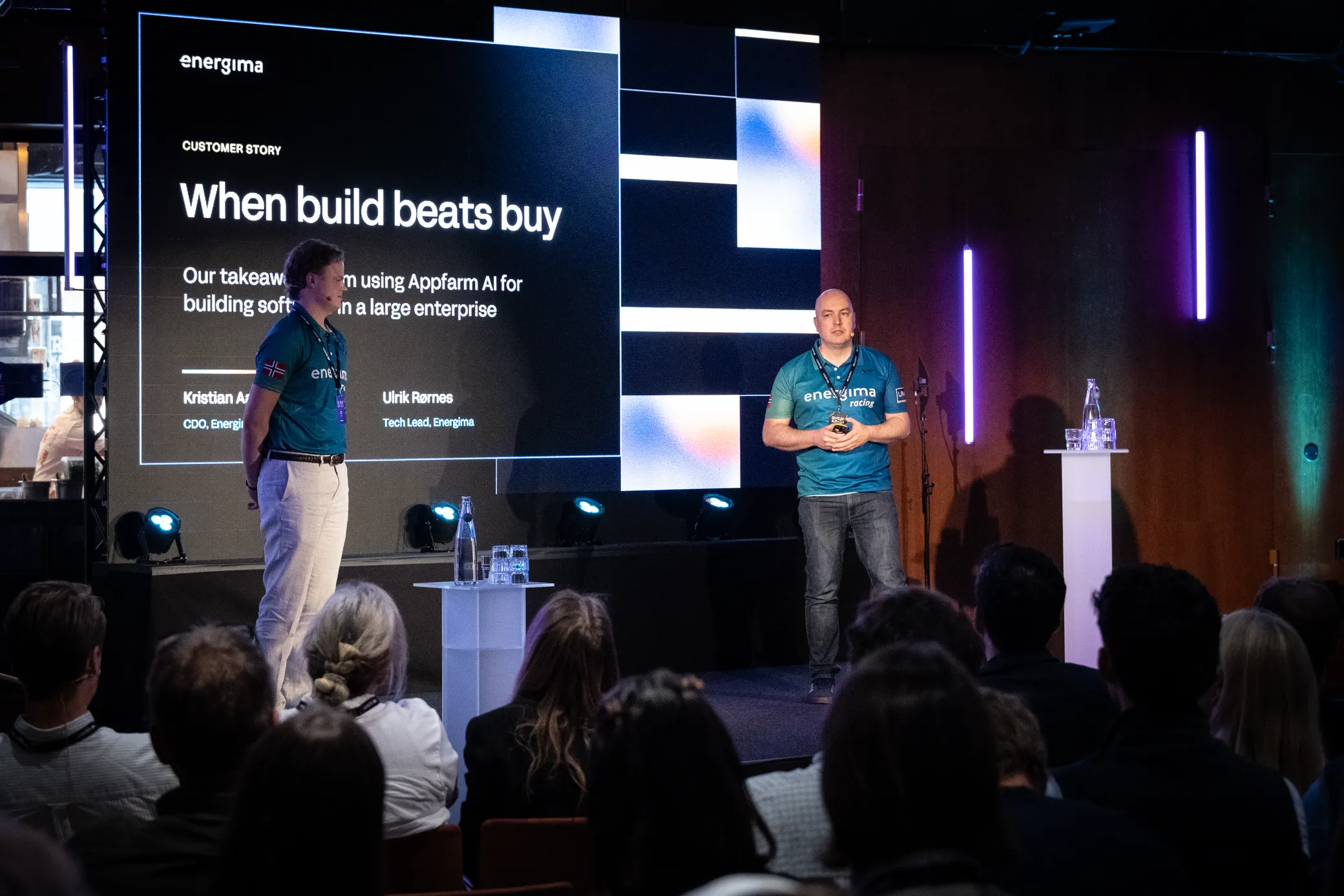 Two presenters on stage in front of a title slide reading When build beats buy, takeaways from using Appfarm AI in a large enterprise