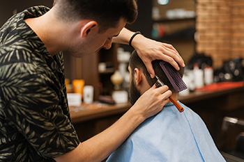Barber cutting a client’s hair in a Southlake TX barbershop, showing the busy atmosphere of a small business.