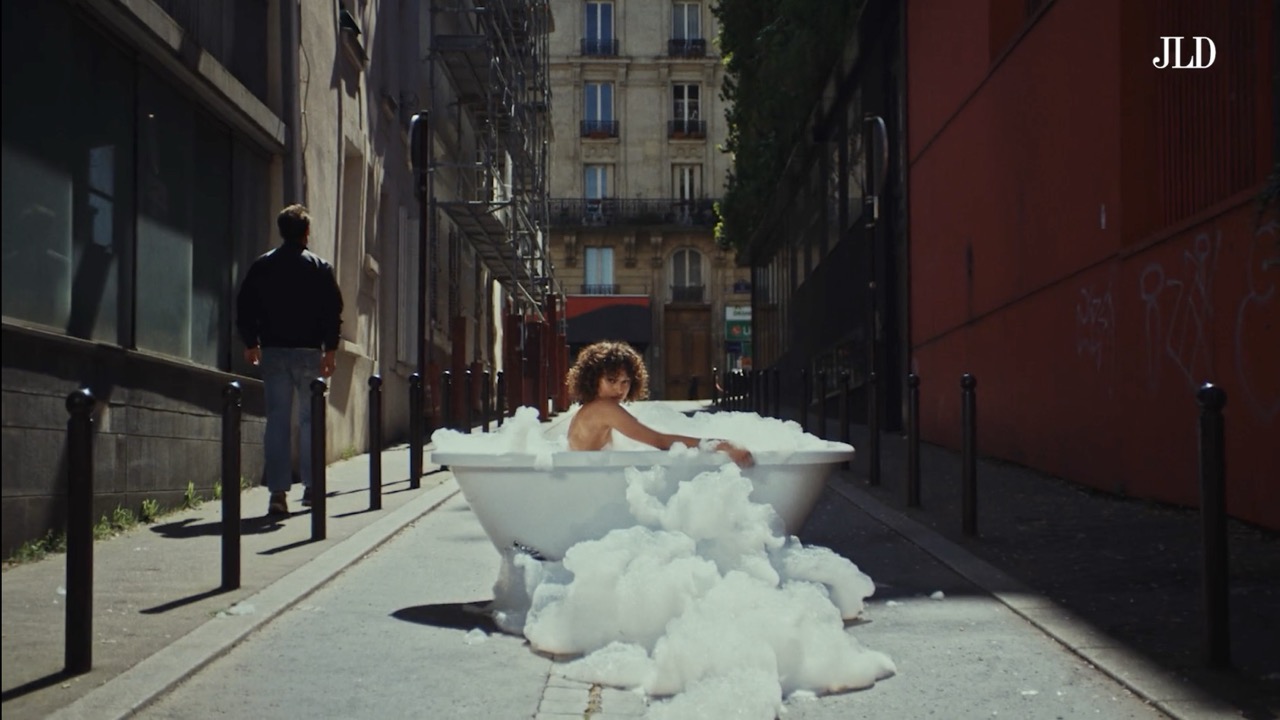 Mannequin cheveux bouclés dans une baignoire au milieu de la rue pour la campagne Jean Louis David 2025/2026