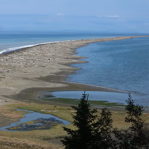 A large body of water sitting next to a sandy beach.