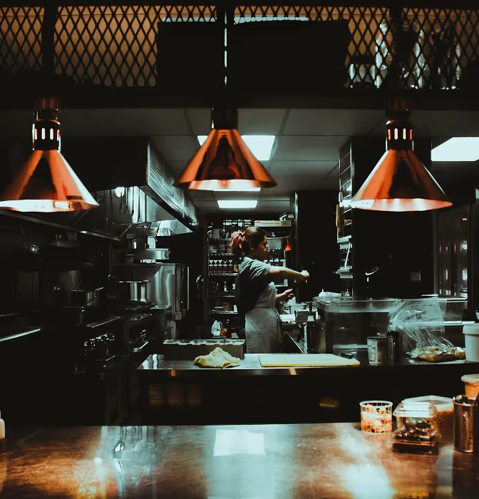 Restaurant kitchen with chef working at the counter and overhead heat lamps