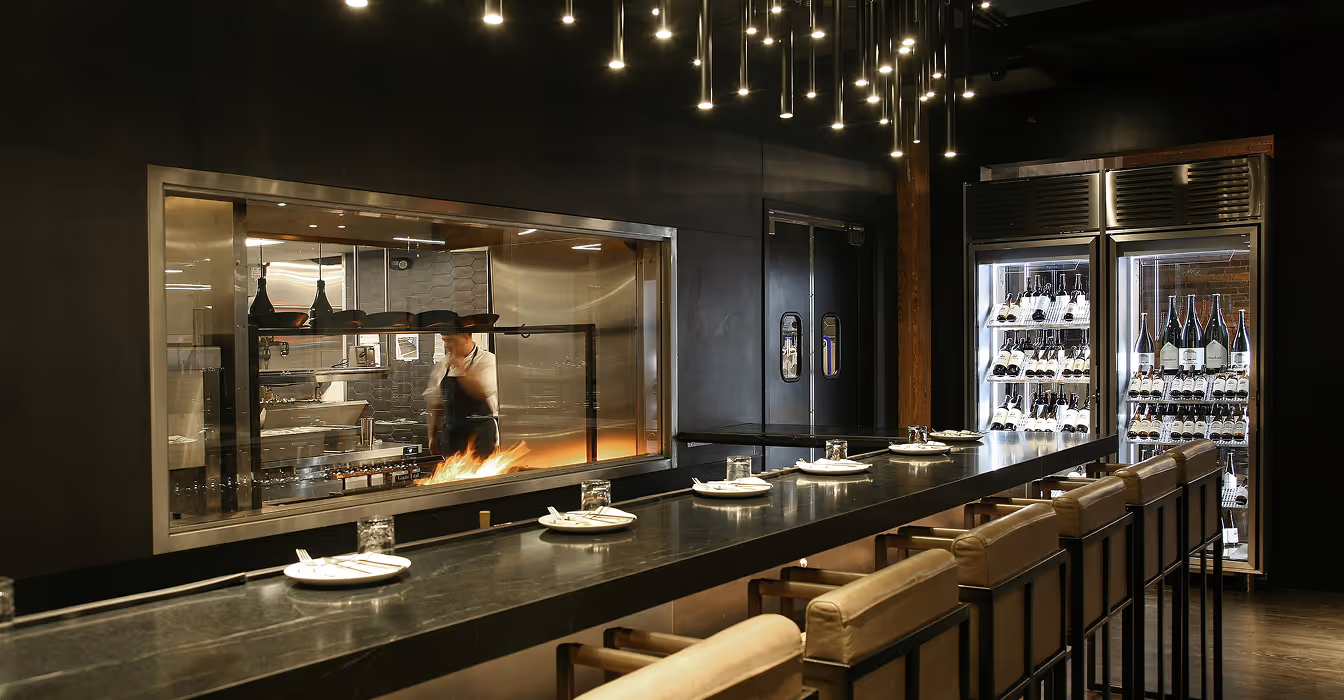 Restaurant interior with open kitchen, bar counter and seating area
