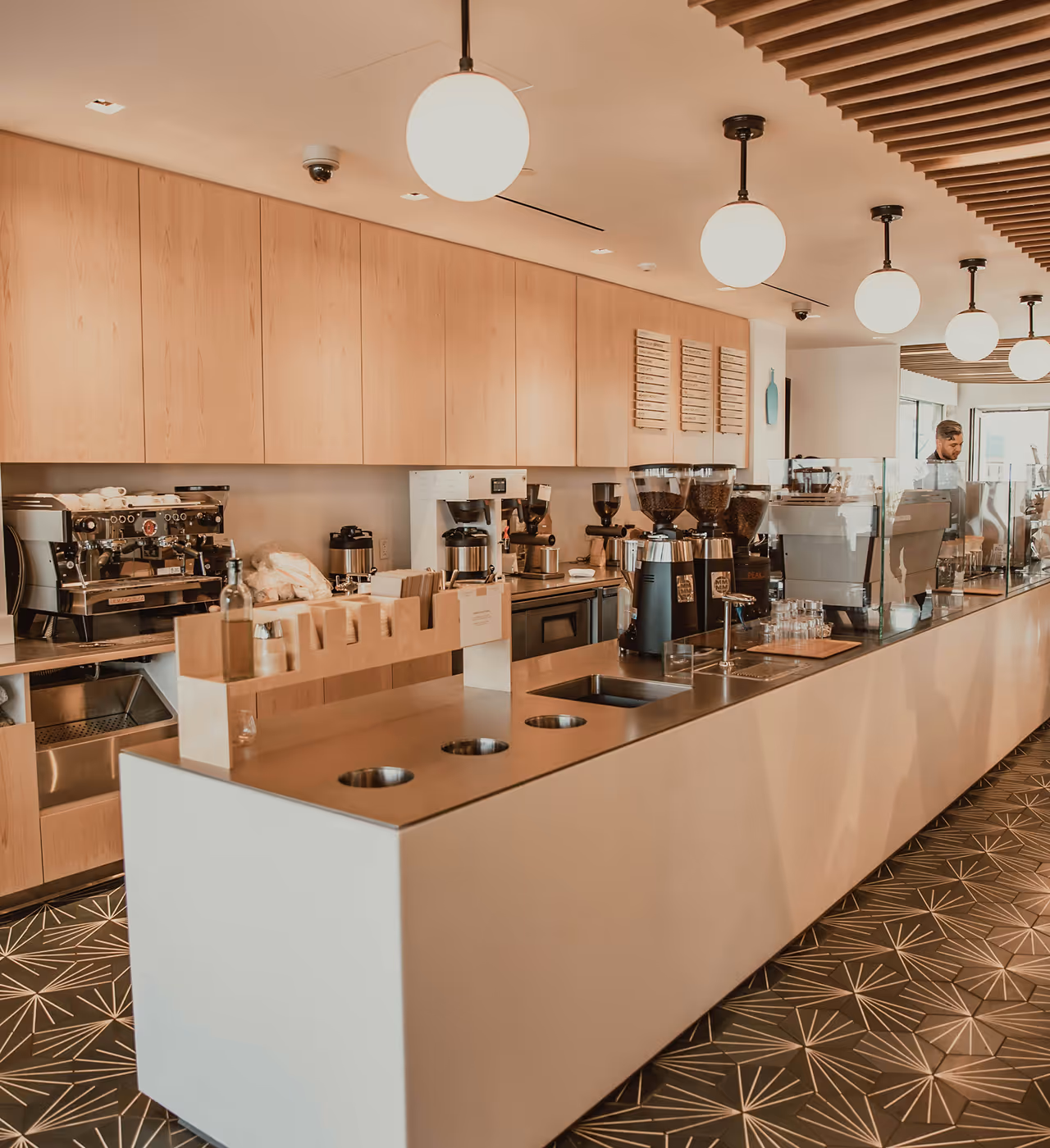 Modern café interior with long counter, coffee machines and pendant lights