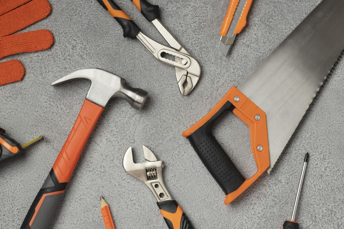 Hammer, saw, wrench, gloves, plyers, screwdrivers all scattered on the floor.