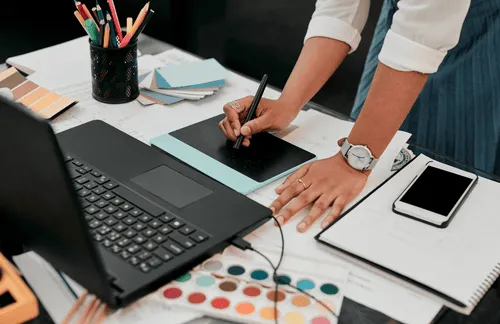 Hands on a laptop with notebooks around them
