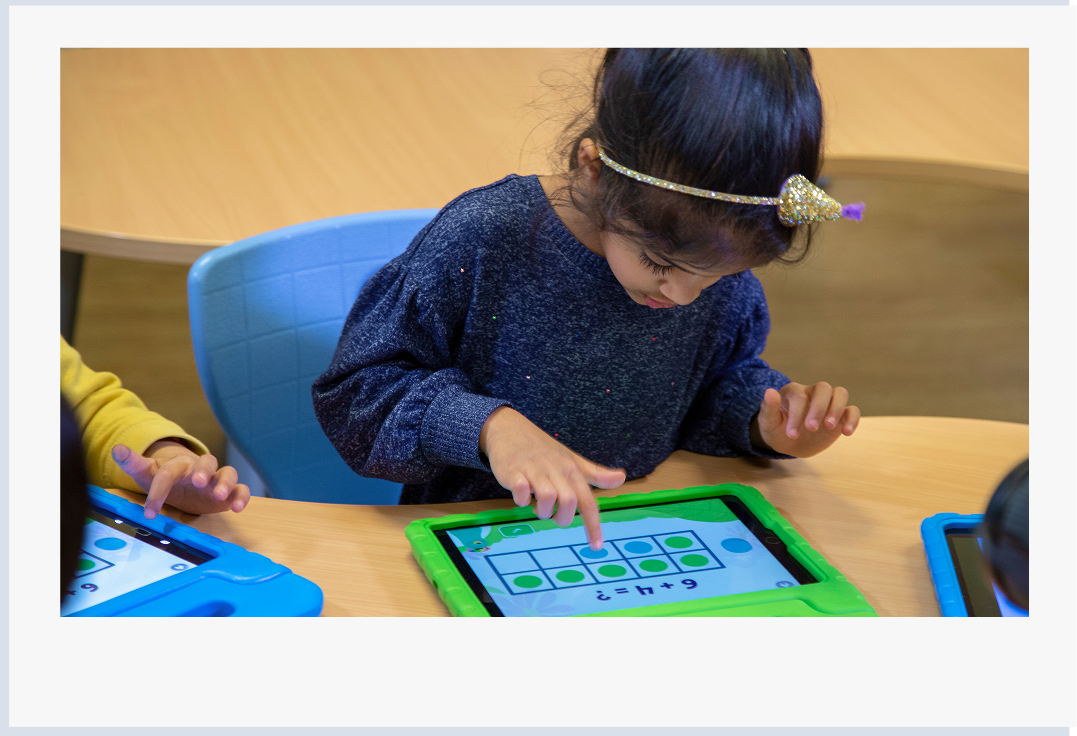 Young girl using the Khan Academy Kids app on a tablet to build early math skills. 