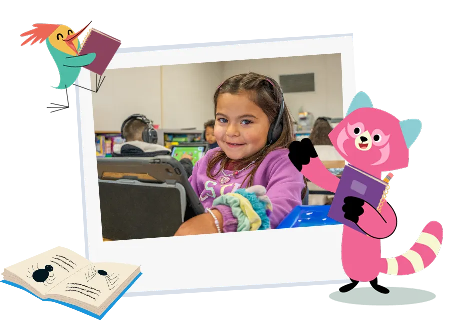 Young girl smiling behind the computer while using a free Khan Kids in a classroom setting.