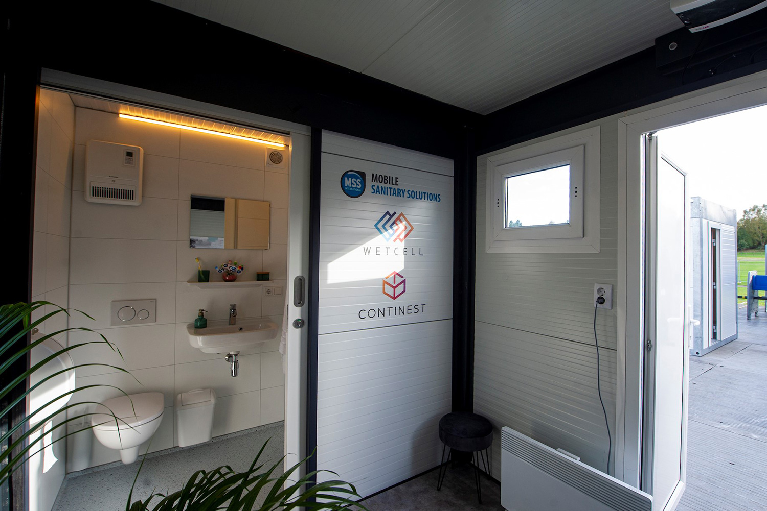 A bathroom with a toilet, sink, and shower that is attached to a CN20 bed unit.  