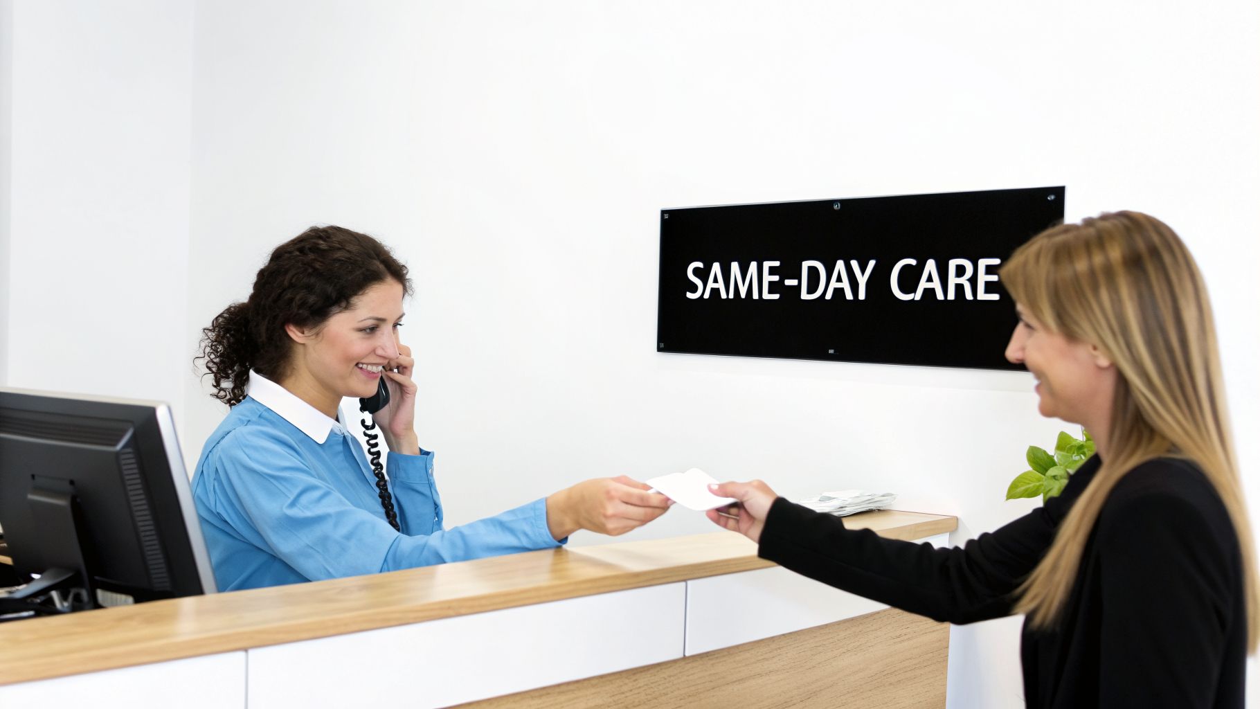 A smiling receptionist on the phone hands a card to a patient at a medical reception desk.