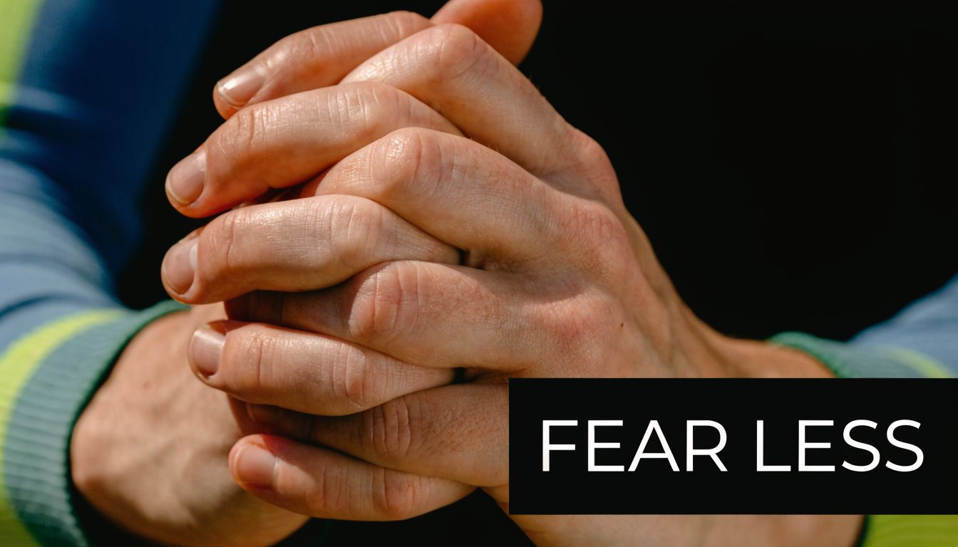A close-up shot of clasped hands demonstrating a calm posture with the text Fear Less visible.