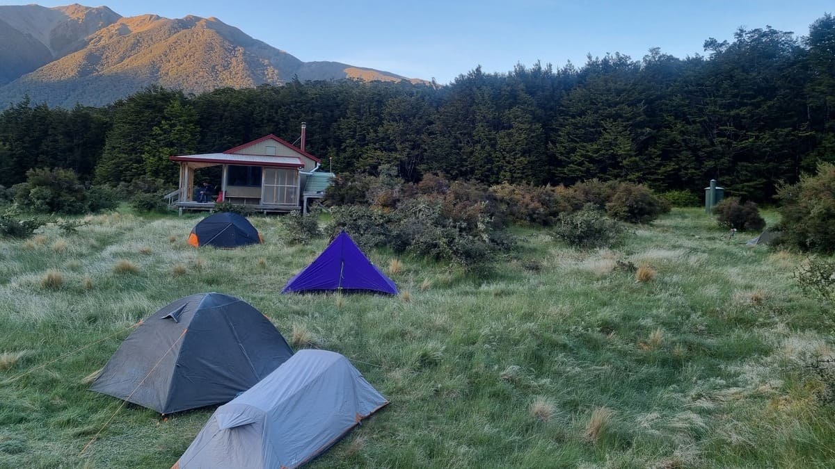 Tents on the grassy area around a backcountry hiking hut.