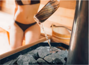 female pouring water (Löyly) onto hot sauna rocks for steam at Sásta Sauna wood-fired facility in Leixlip, Co. Kildare.