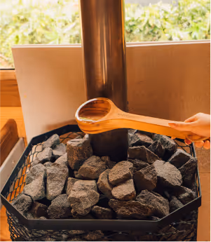 Hand pouring water onto hot sauna stones (Löyly) to create therapeutic steam at Sásta Sauna in Leixlip, Co. Kildare.
