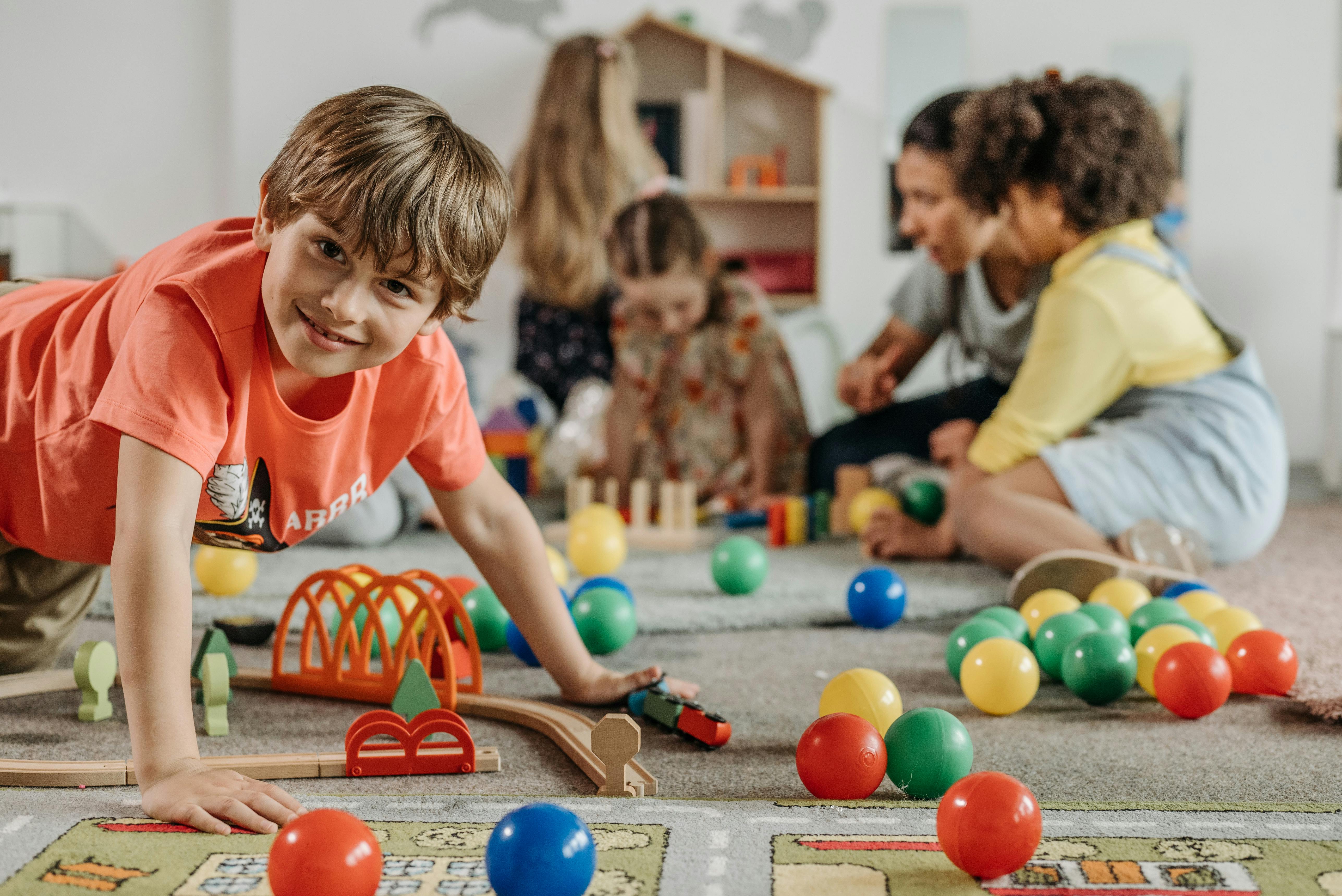 Preschoolers playing with toys on the floor of a classroom