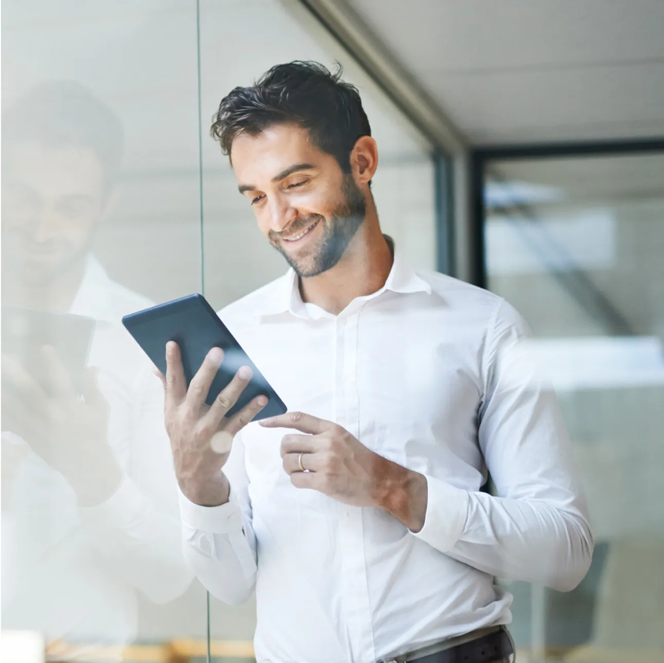 Man in a white shirt smiling and looking down.