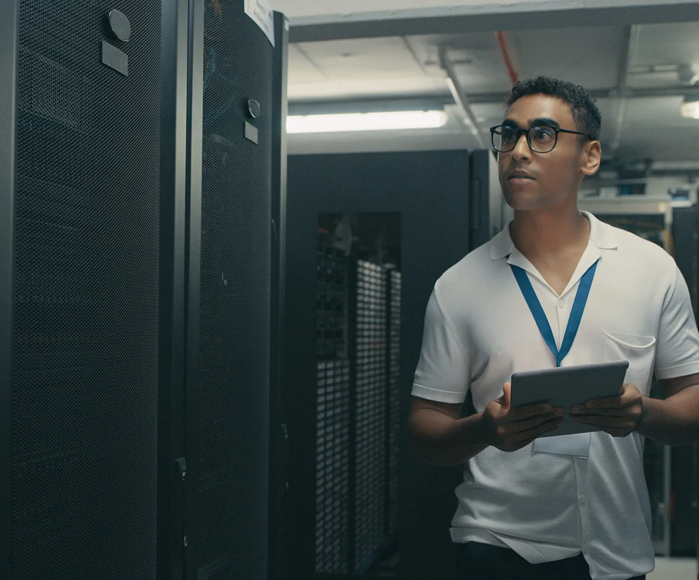 Two business professionals walking and talking through a modern glass entrance of an office building, with plants and urban buildings visible outside.