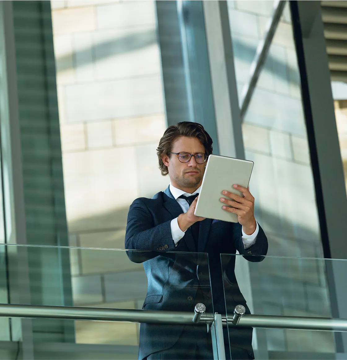 A man in a suit holding a tablet.