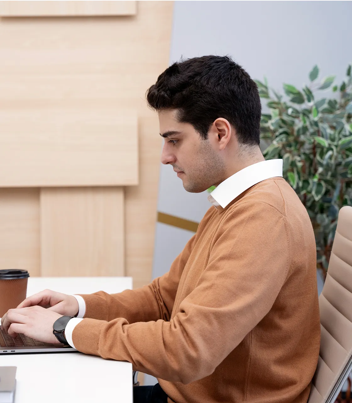 A man sitting at a desk using a laptop computer.