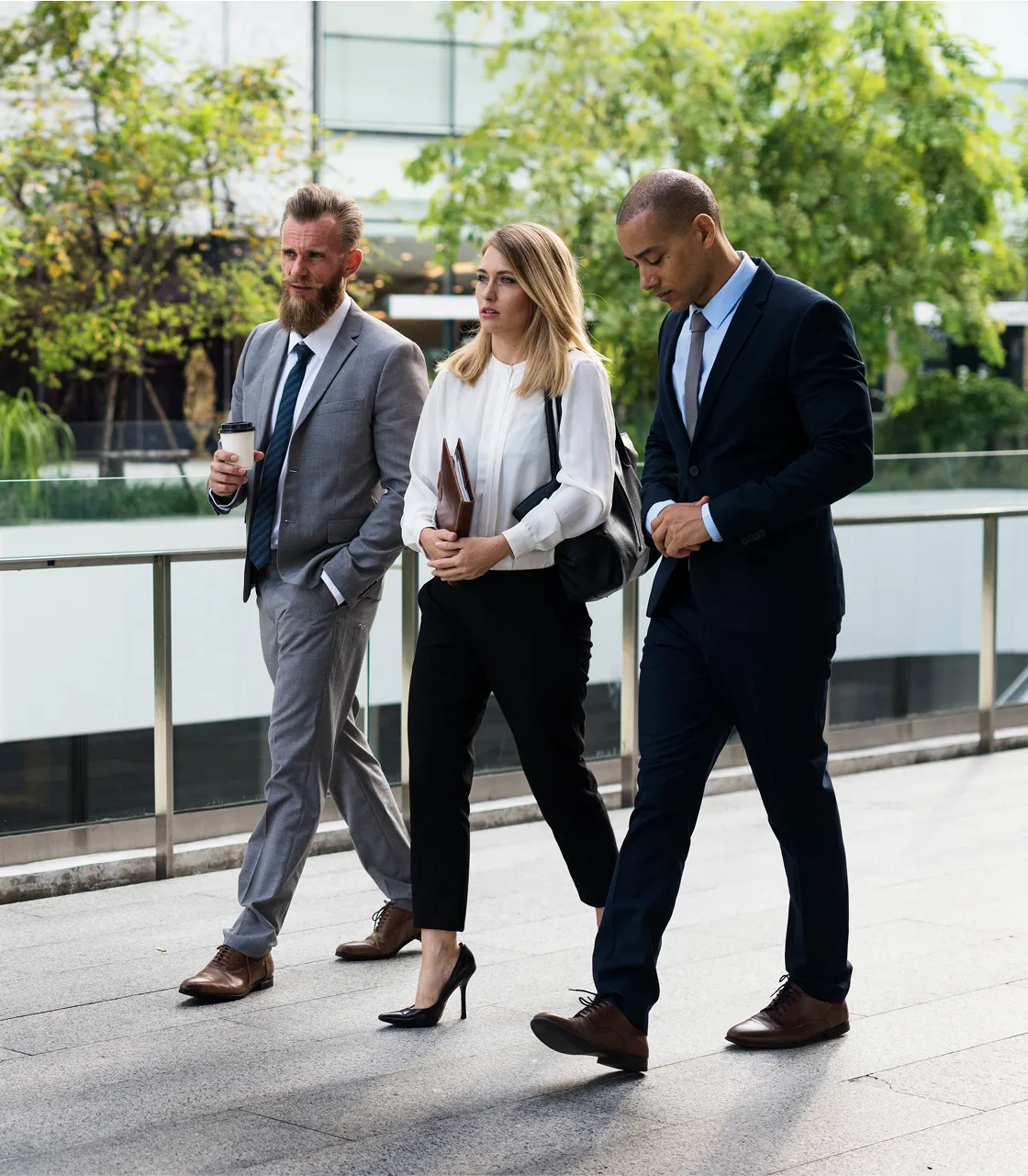 A group of business people walking down a sidewalk.