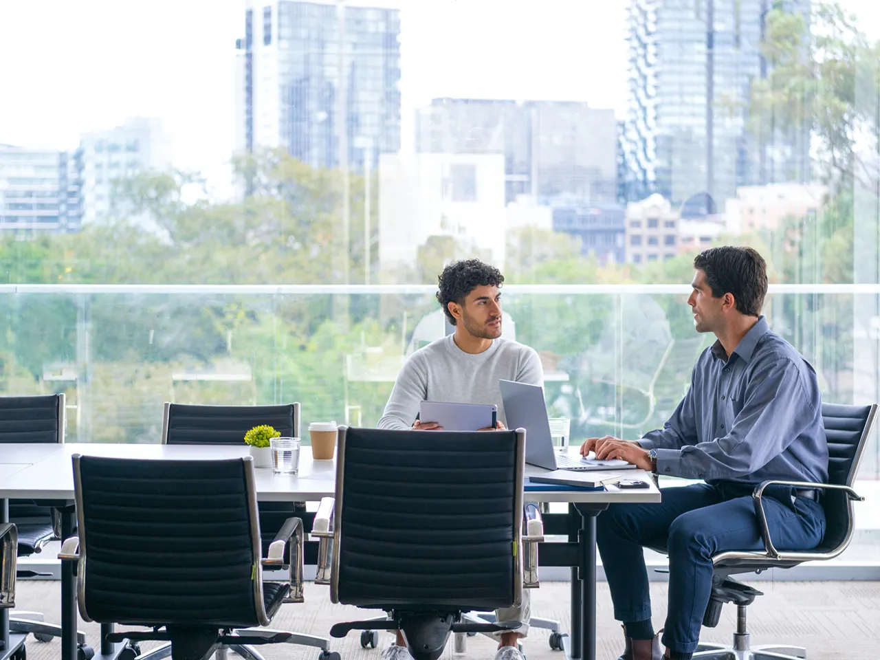 A couple of men sitting at a table with laptops.