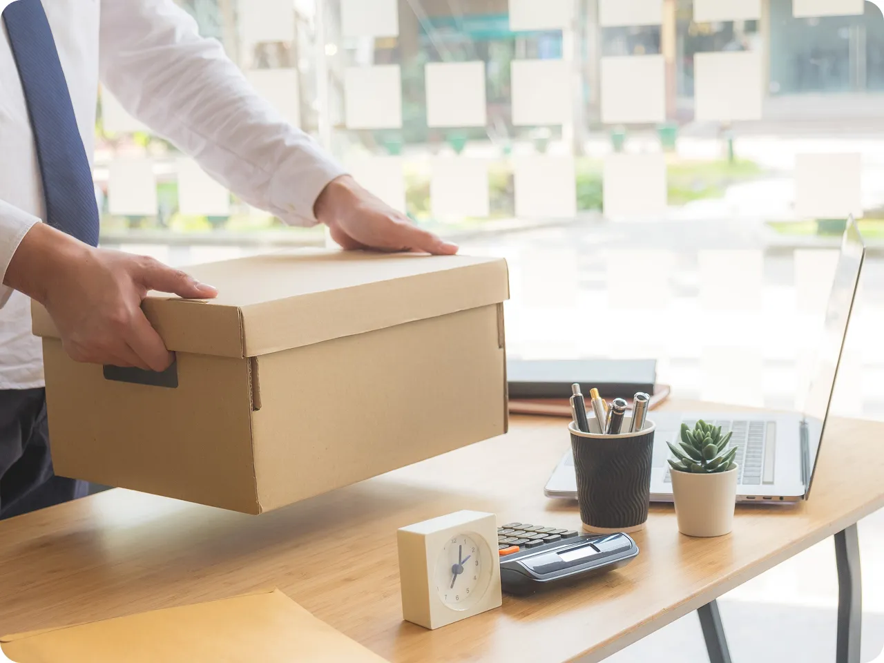 A person holding a box over a desk.