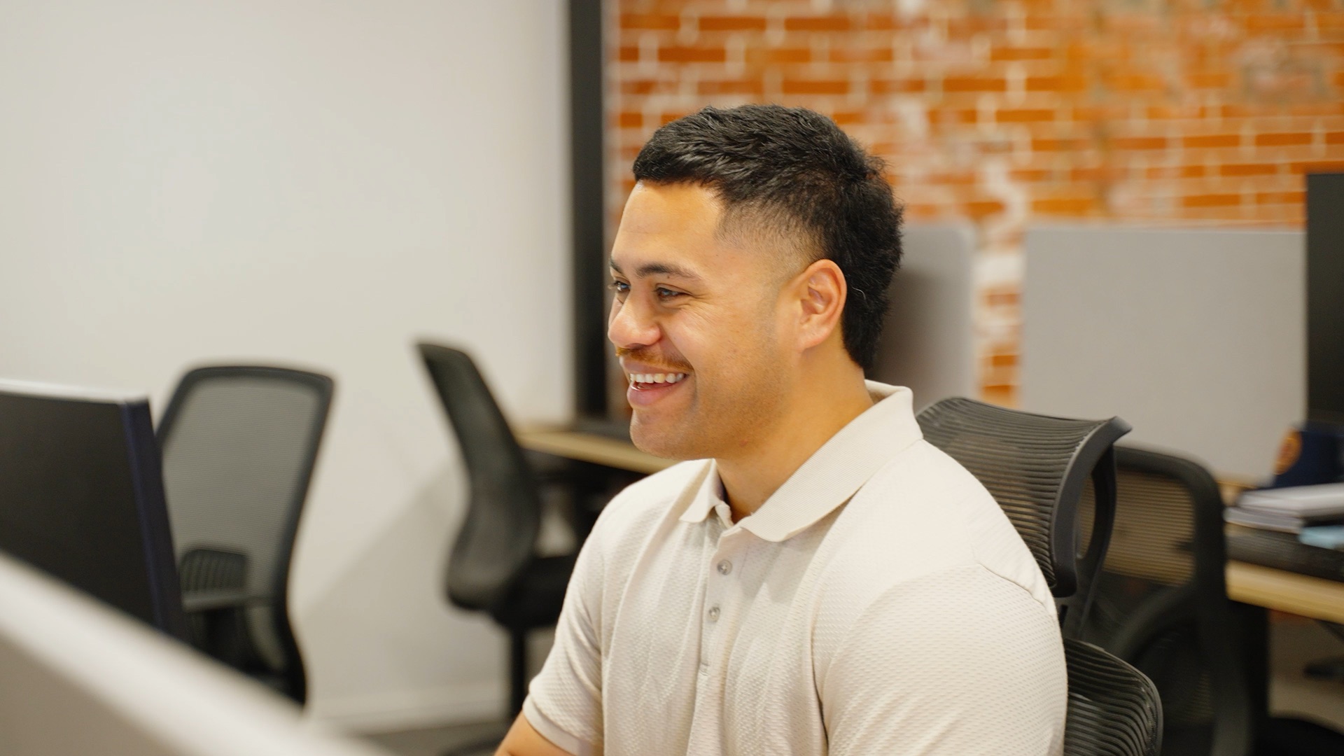 Still from the Gerrards Careers film, a team member laughing at his desk in the office