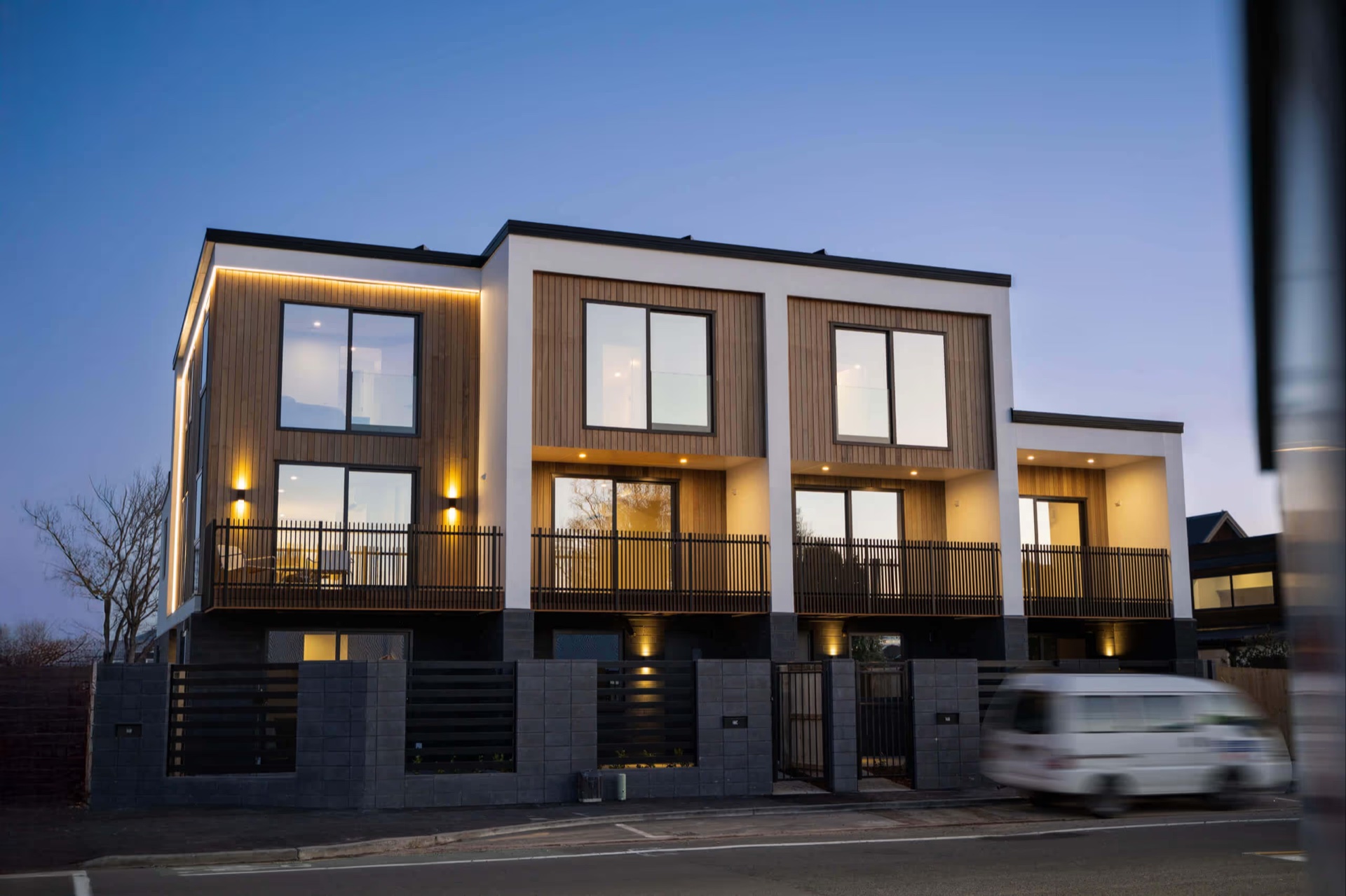 Completed M Group townhouses at dusk with warm interior light and timber cladding