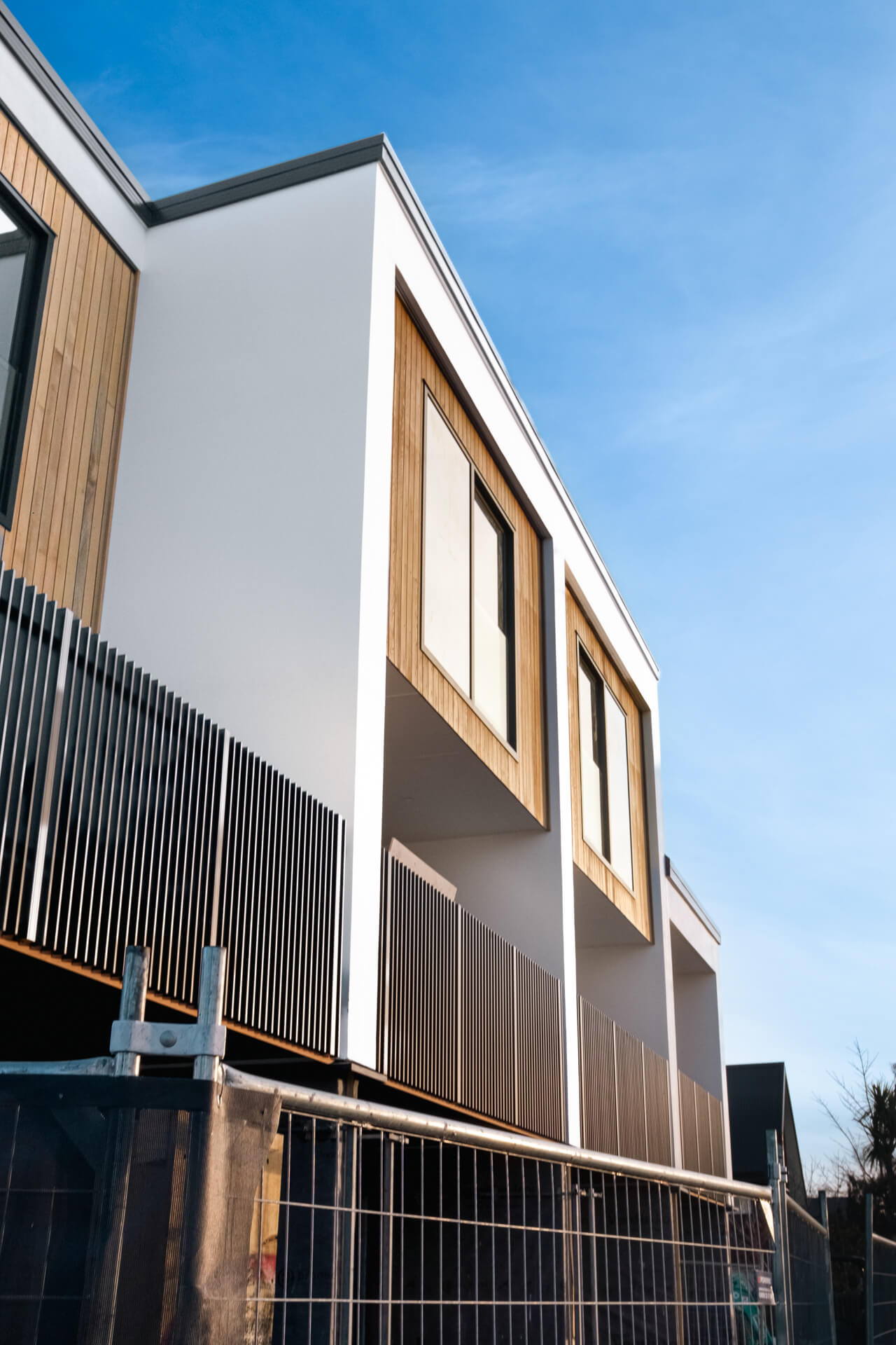 A townhouse under construction with temporary fencing and timber cladding going on