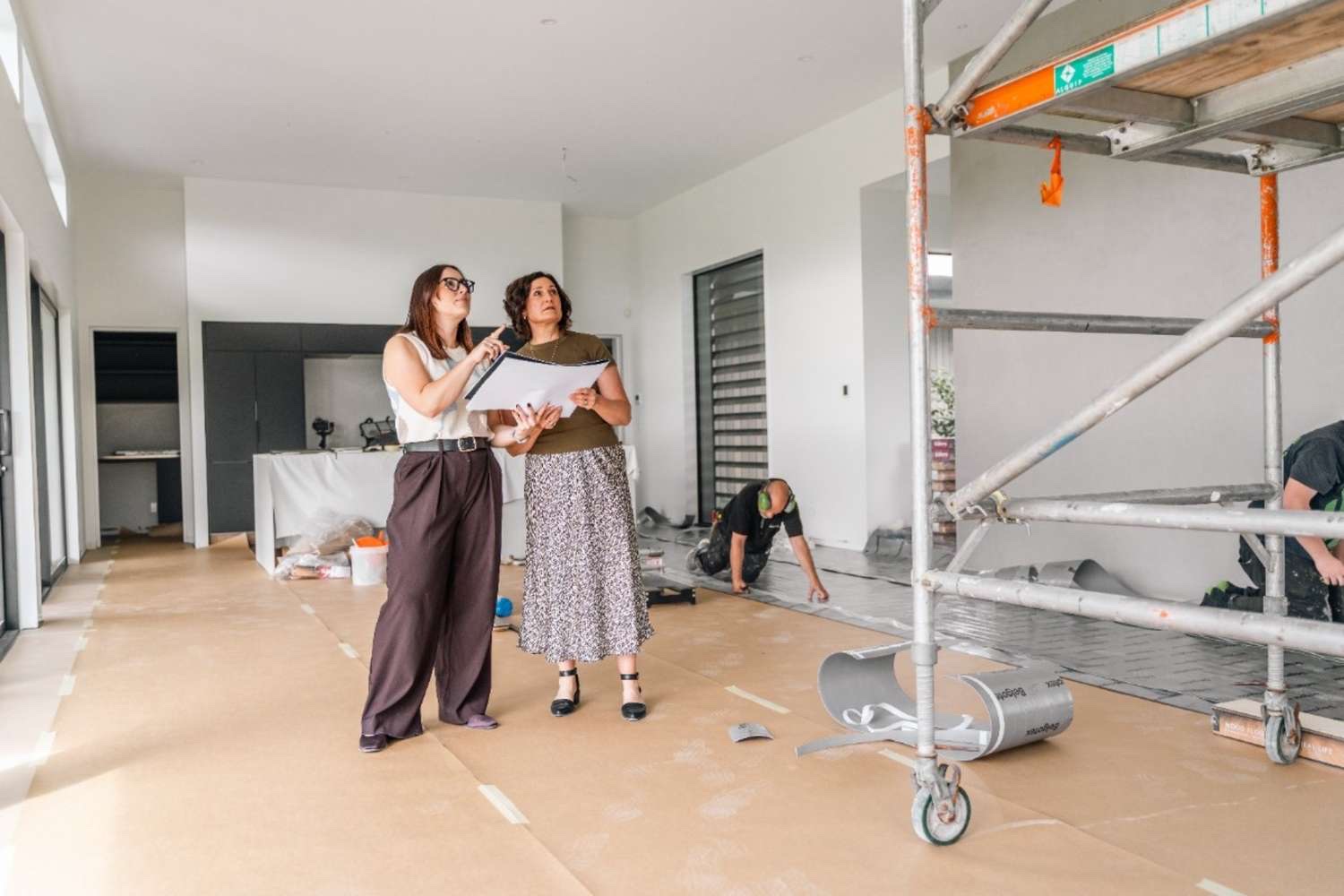 Two LH Design team members reviewing plans in a room being renovated
