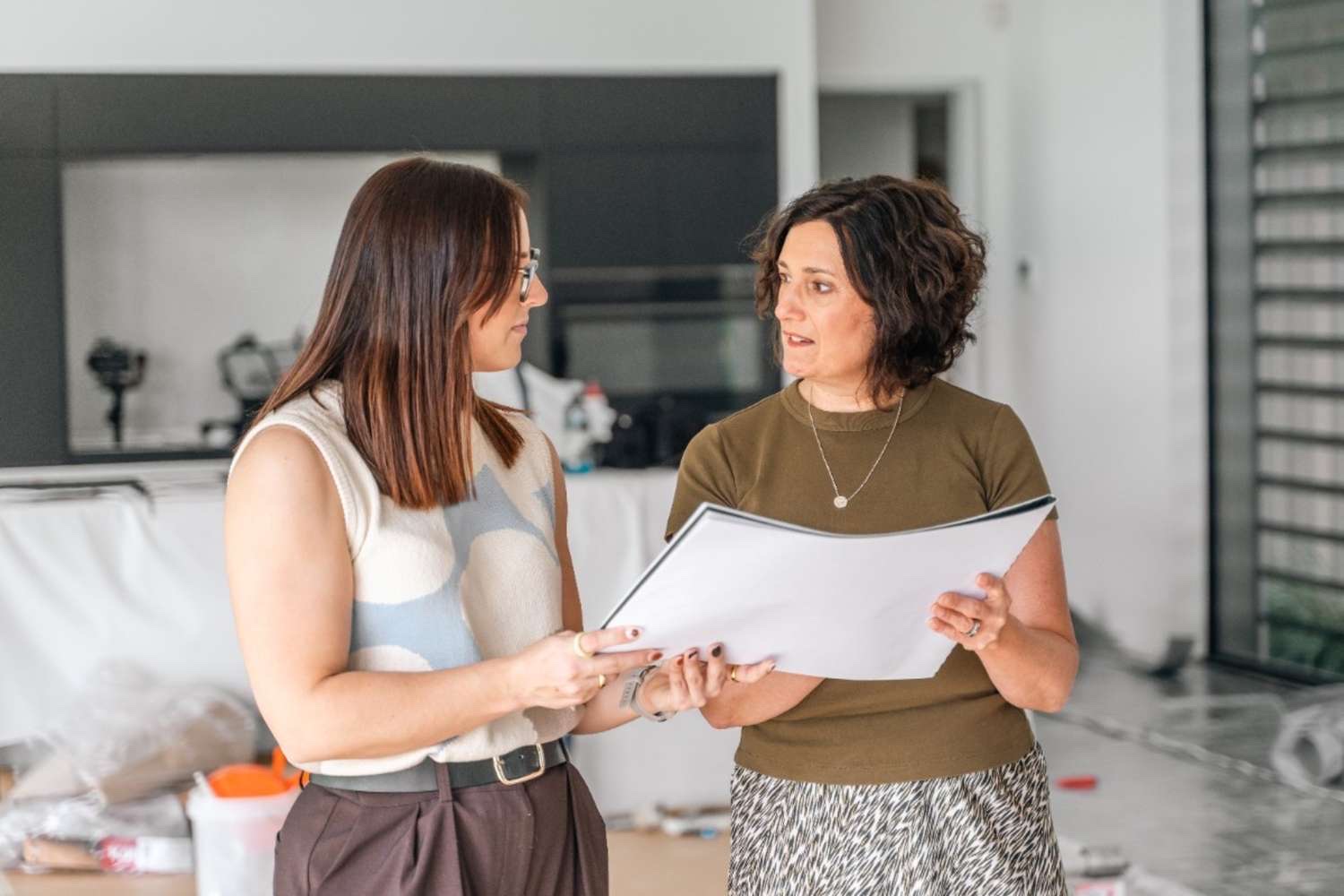Two people reviewing a sample folder in a kitchen under construction